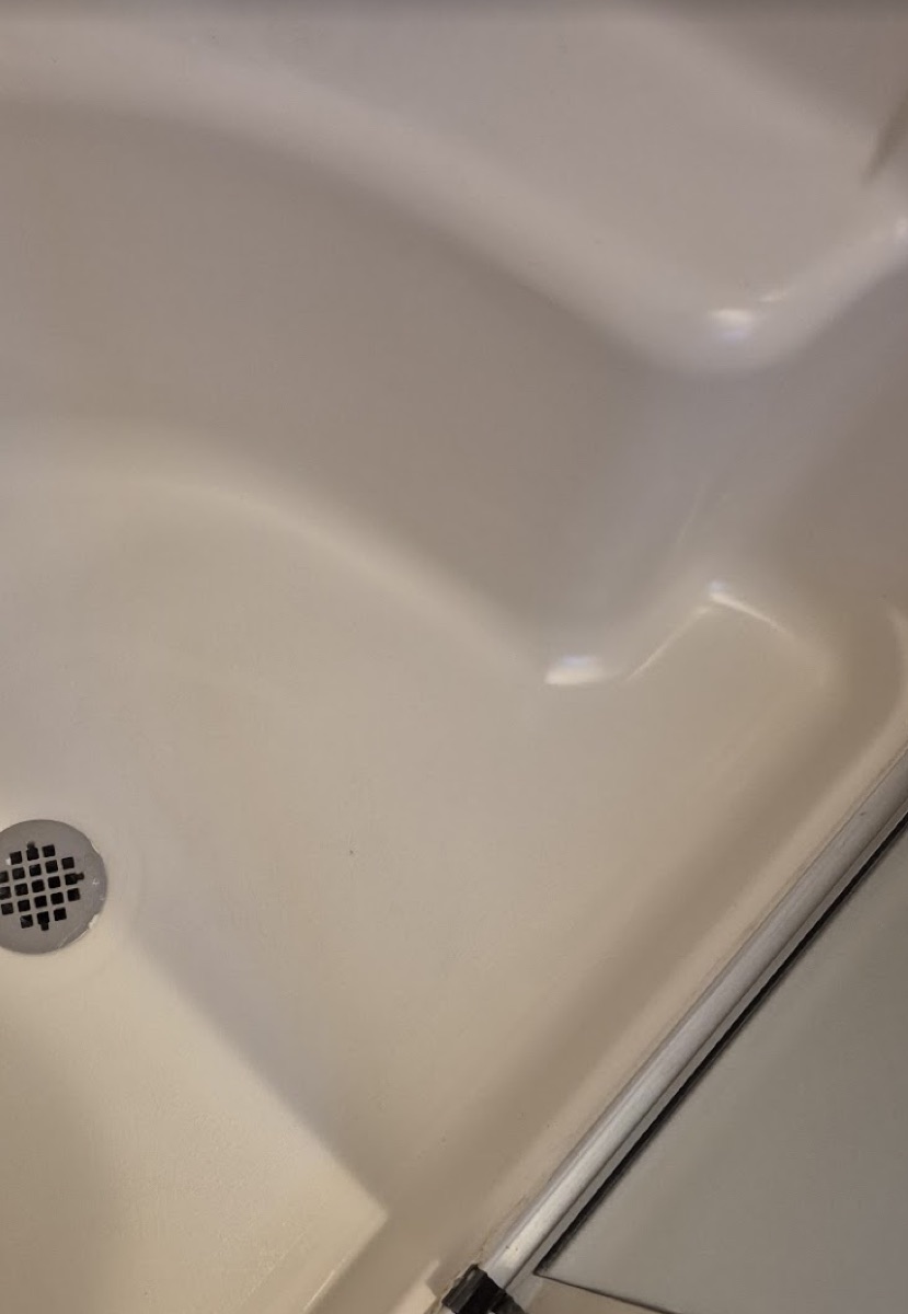The same shower pan after MR Tub Repair refinished it to a clean, glossy white