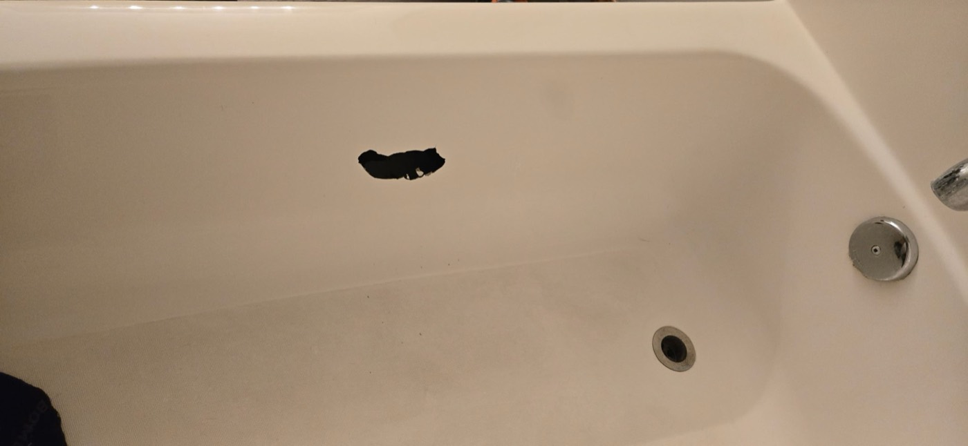 Bathtub with a hole in the floor before repair